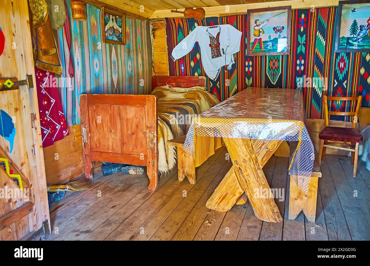 YABLUNYTSYA, UKRAINE - 24 JUILLET 2021 : la chambre vintage dans une petite maison Hutsul avec lit, table, tapis sur les murs, Mountain Valley Peppers artisanat v Banque D'Images