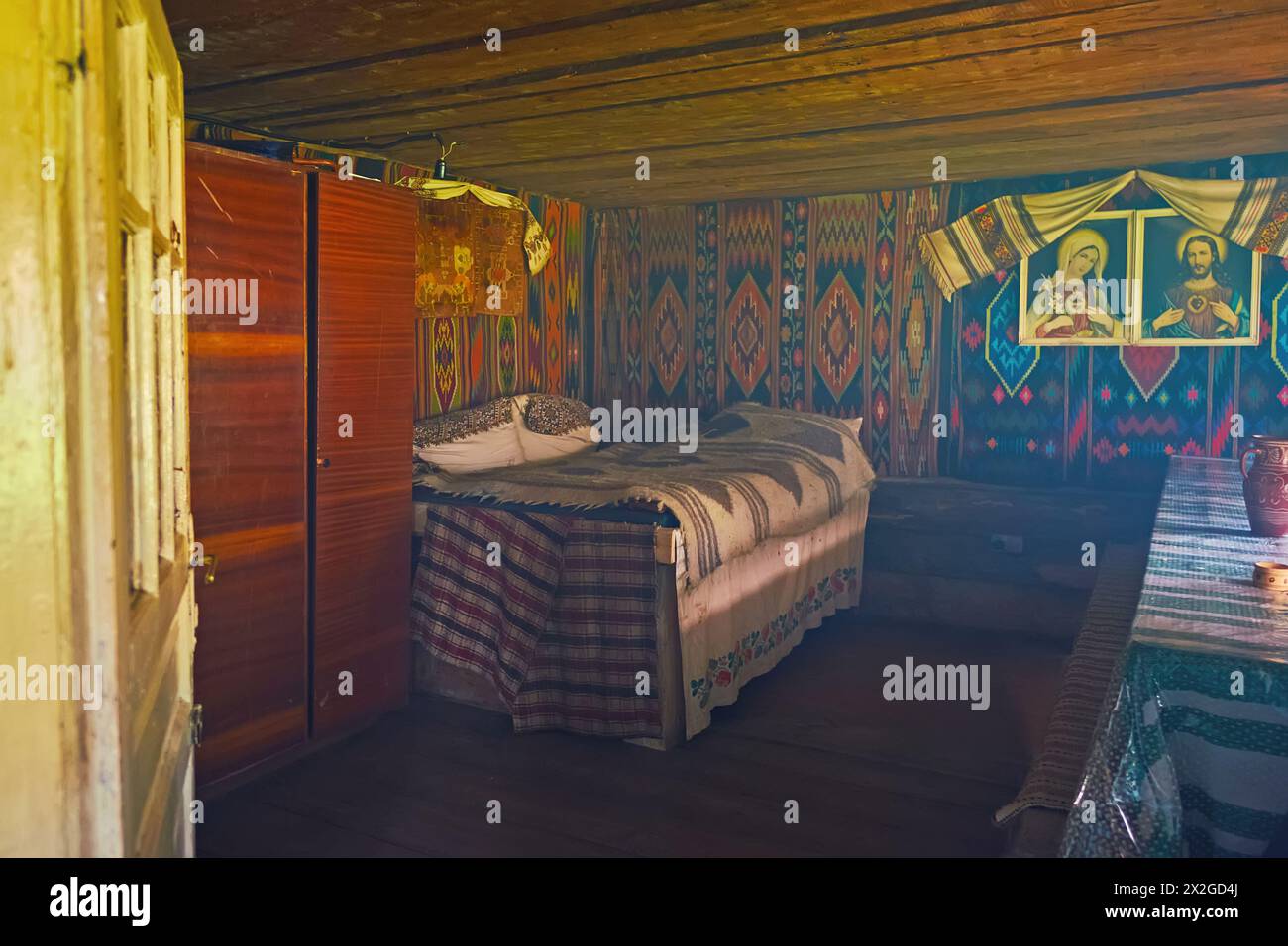 YABLUNYTSYA, UKRAINE - 24 JUILLET 2021 : la chambre vintage dans la maison Hutsul en bois avec des tapis sur les murs, des icônes et des serviettes décoratives rushnyk, montagne va Banque D'Images