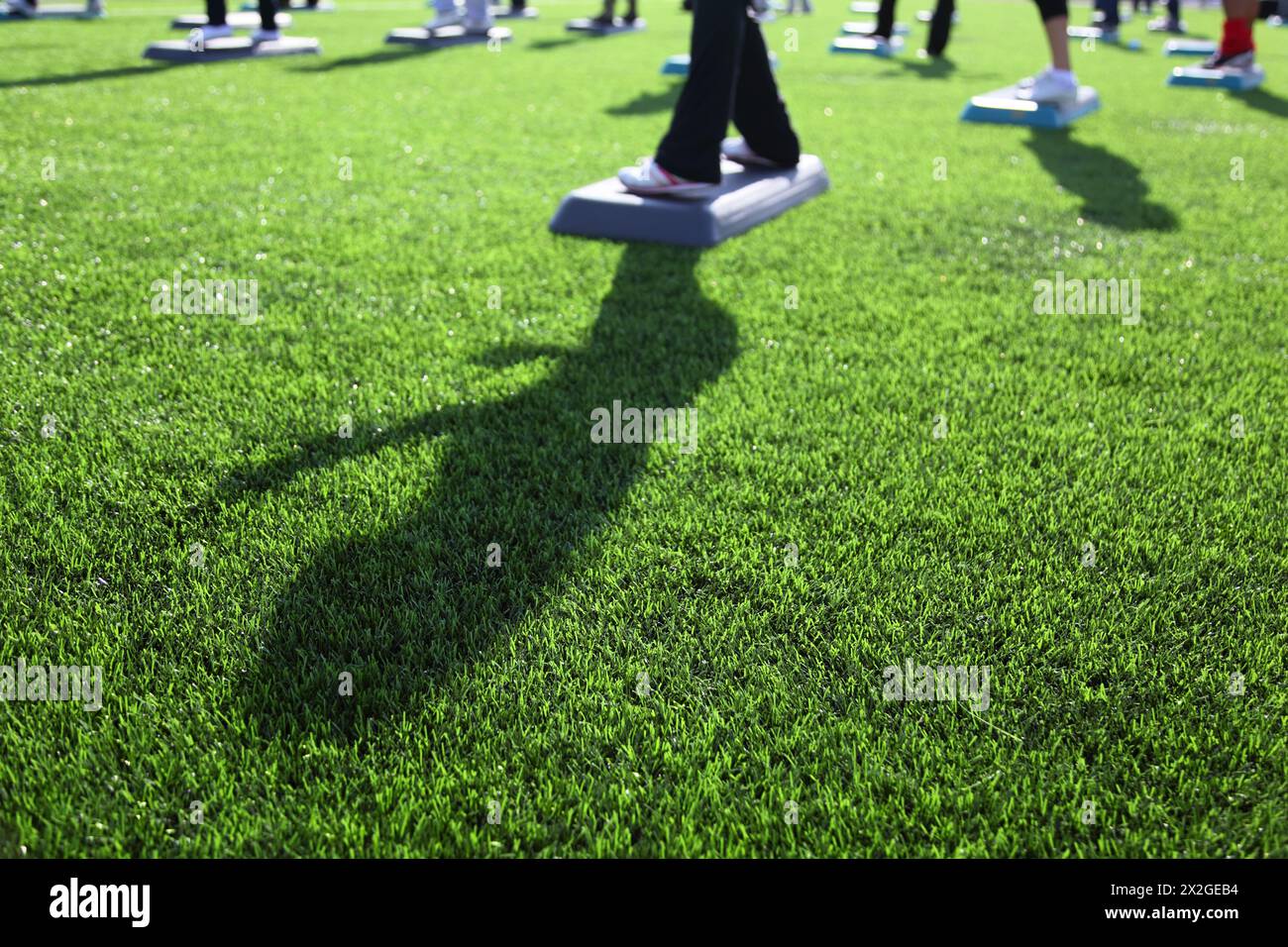 fitness de masse au stade au jour ensoleillé d'automne, concentrez-vous sur l'herbe verte ; pieds et ombre dans le cadre Banque D'Images