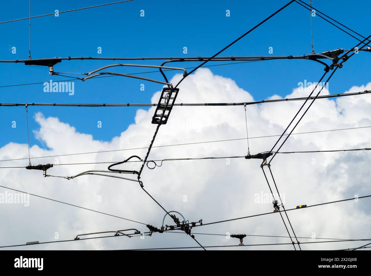 Câblage électrique du trafic de tramway et de bus de la ville - en arrière-plan un puissant nuage dans le ciel bleu Banque D'Images