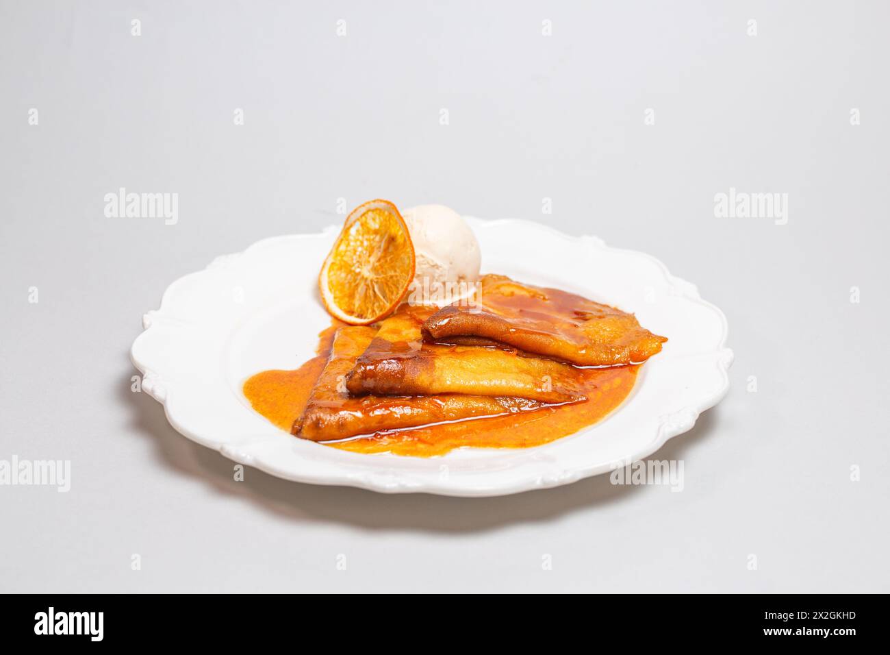 Offrez-vous un dessert alléchant de crêpes baignées d'une sauce orange et couronnées de crème glacée crémeuse pour un délice délicieux. Banque D'Images