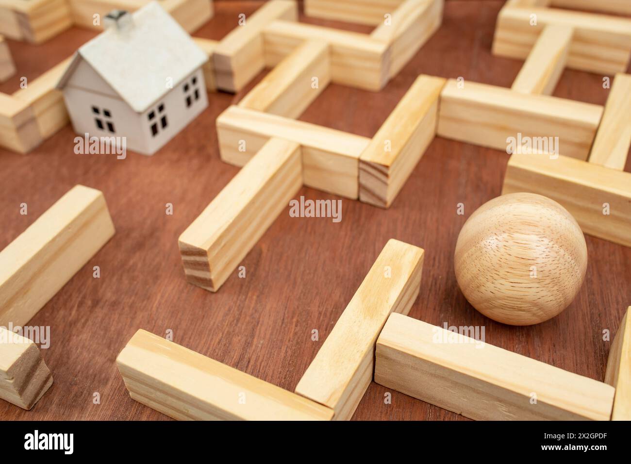 Maison blanche miniature dans un labyrinthe en bois, labyrinthe en bois fait avec des blocs de bois et une sphère de bois trouvant labyrinthe concept de sortie, soft focus close up Banque D'Images
