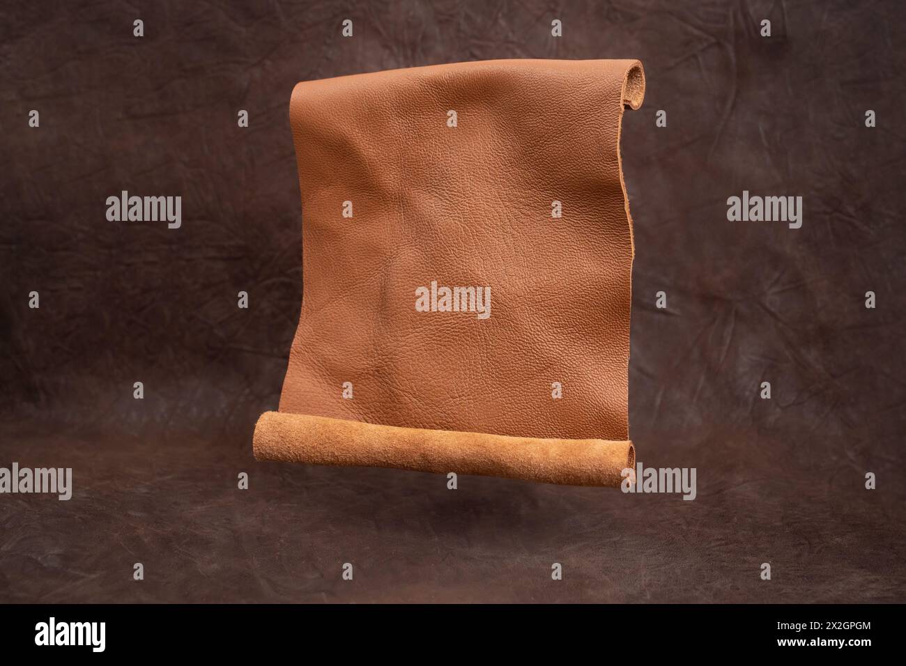 Rouleau en cuir véritable ouvert lévitant sur fond de vignette marron, texture abstraite Banque D'Images
