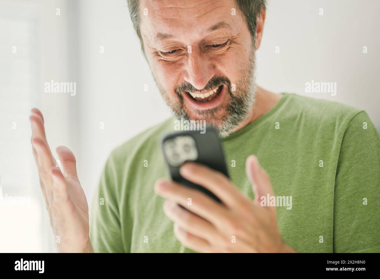 Homme heureux a reçu un message texte satisfaisant sur smartphone mobile, focus sélectif Banque D'Images