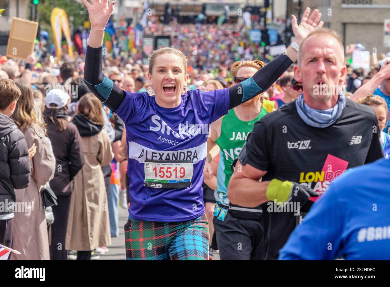 Marathon de Londres 2024 : une femme qui court en aide à l'association caritative Stroke Association agite les deux bras en l'air pendant le marathon de Londres Banque D'Images