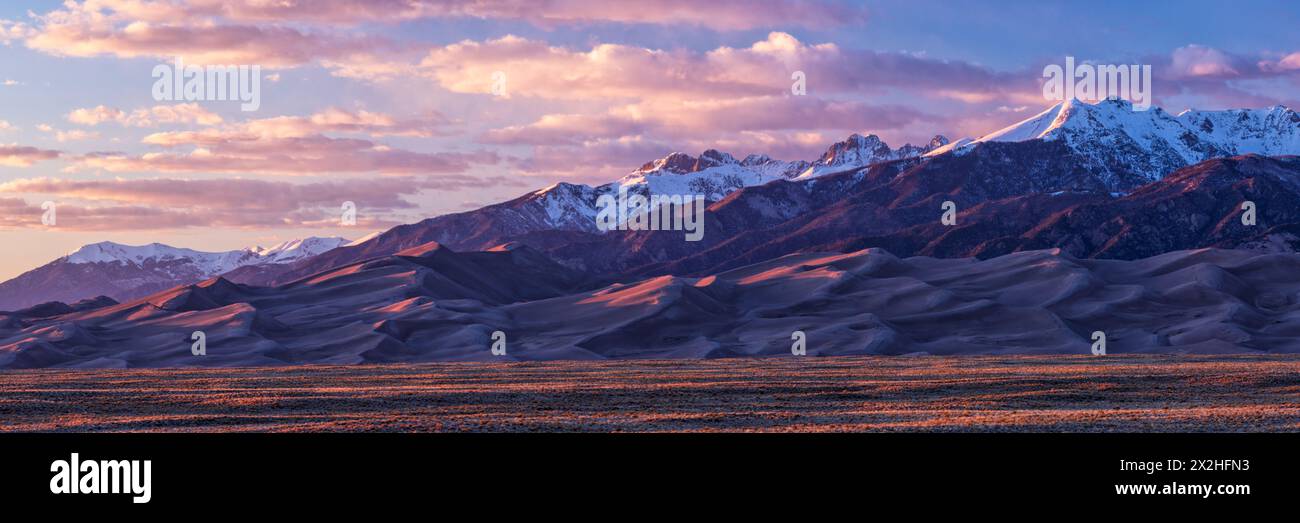 La lumière Golden Hour réchauffe les sommets des montagnes Sangre de Cristo et les sommets des dunes du parc national Great Sand Dune, Colorado Banque D'Images
