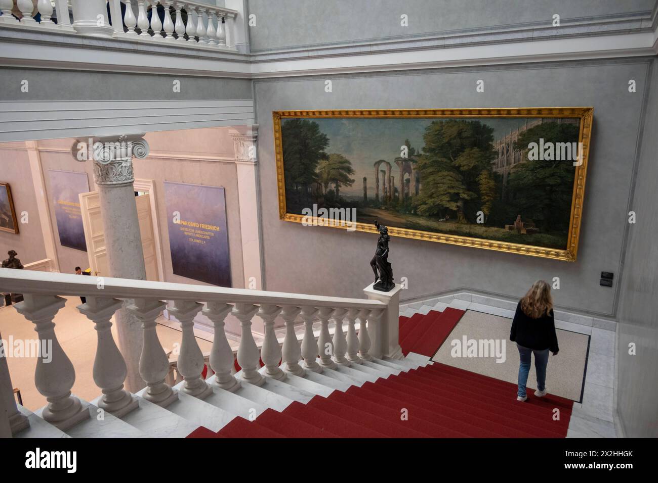 Riesiges Oelgemaelde Gotische Klosterruine und Baumgruppen von Karl Friedrich Schinkel und schwarze Skulpur Tanzende Bacchantin von Carl Friedrich Echtermeyer auf einem Treppensockel im Treppenhaus mit Besucherin, im Rahmen der Sonderausstellung unendliche Landschaften vom Maler Romantik Caspar David Friedrich galerie, in der Alten Nationalam, in der Alten Miterte format, Berlin,, Berlin, Berlin, 19.04.2024 nur fuer redaktionelle Zwecke, usage éditorial exclusif Alte Nationalgalerie etc - Berlin *** peinture à l'huile géante ruines du monastère gothique et groupes d'arbres de Karl Friedrich Schinkel et sculpture noire dansant Bacch Banque D'Images