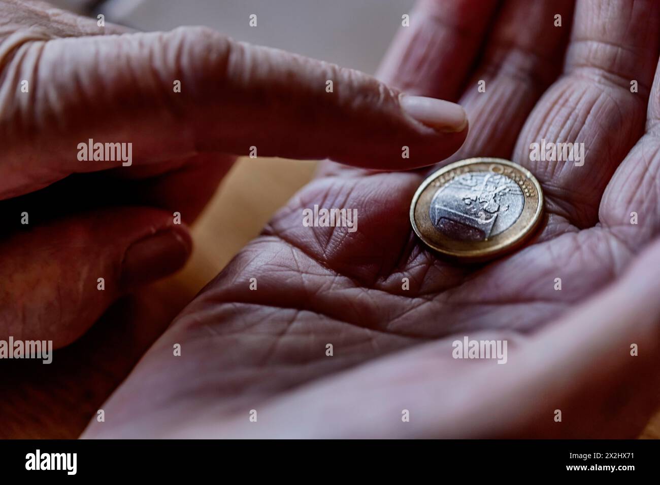 Une pièce en euros dans la main ridée d'un vieillard, symbolisant la pauvreté et la pauvreté chez les personnes âgées Banque D'Images