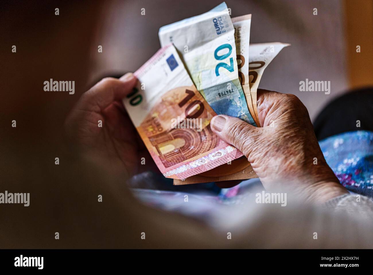 Une personne âgée aux mains froissées compte son argent à la maison dans son appartement et tient les billets de banque dans sa main, Cologne, Rhénanie du Nord-Westphalie, Allemagne Banque D'Images