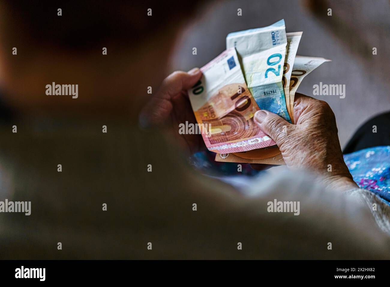 Une personne âgée aux mains froissées compte son argent à la maison dans son appartement et tient les billets de banque dans sa main, Cologne, Rhénanie du Nord-Westphalie, Allemagne Banque D'Images