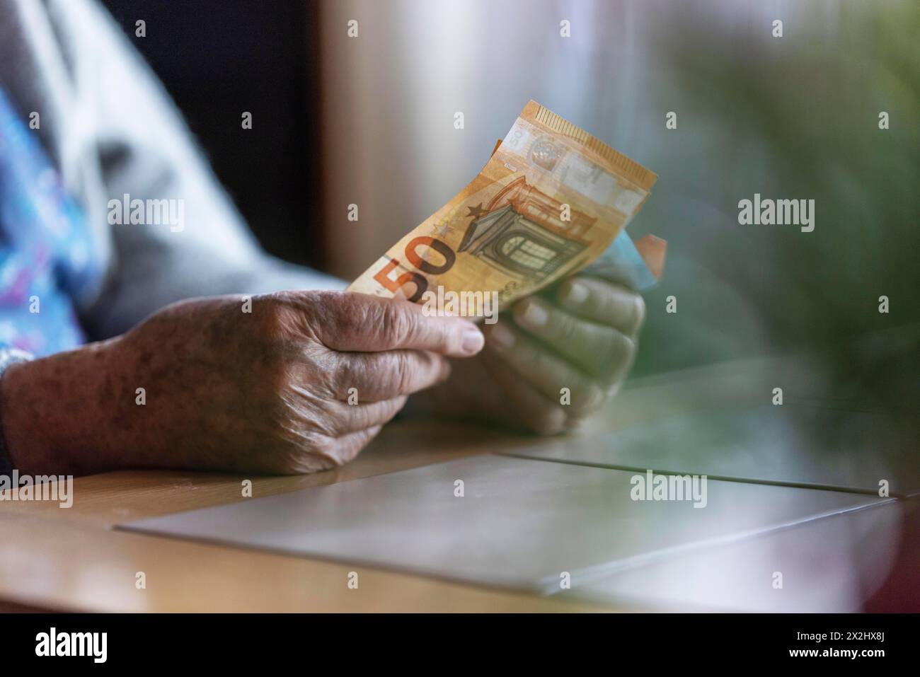 Une personne âgée aux mains froissées compte son argent à la maison dans son appartement et tient les billets de banque dans sa main, Cologne, Rhénanie du Nord-Westphalie, Allemagne Banque D'Images