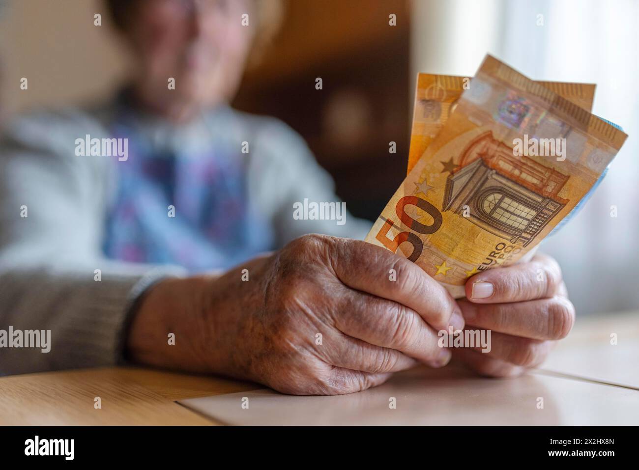 Une personne âgée aux mains froissées compte son argent à la maison dans son appartement et tient les billets de banque dans sa main, Cologne, Rhénanie du Nord-Westphalie, Allemagne Banque D'Images