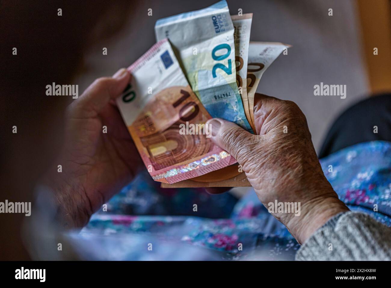 Une personne âgée aux mains froissées compte son argent à la maison dans son appartement et tient les billets de banque dans sa main, Cologne, Rhénanie du Nord-Westphalie, Allemagne Banque D'Images