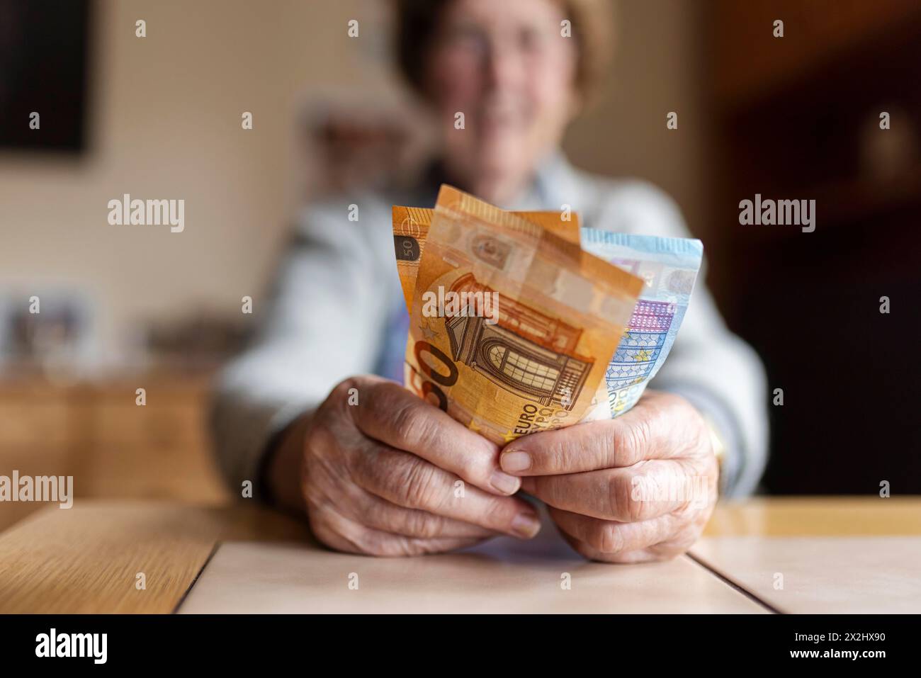 Une personne âgée aux mains froissées compte son argent à la maison dans son appartement et tient les billets de banque dans sa main, Cologne, Rhénanie du Nord-Westphalie, Allemagne Banque D'Images