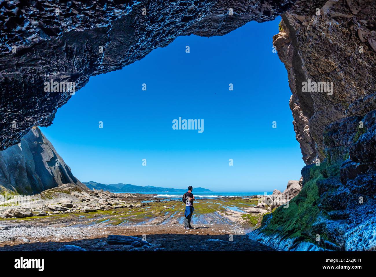 Un randonneur dans la grotte de mer de la crique d'Algorri sur la côte dans le flysch de Zumaia, Gipuzkoa. Pays Basque Banque D'Images
