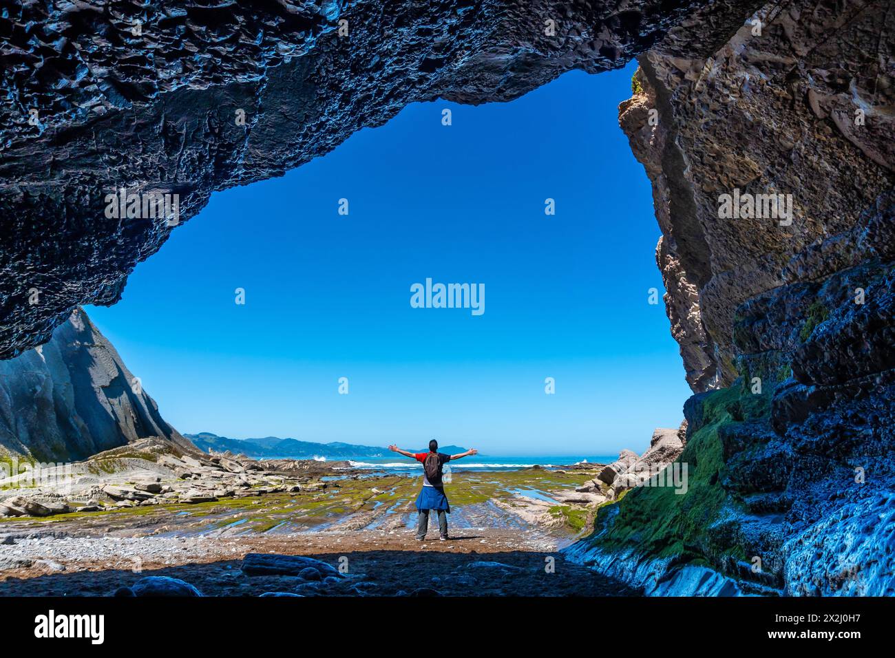 Un randonneur dans la grotte de mer de la crique d'Algorri sur la côte dans le flysch de Zumaia, Gipuzkoa. Pays Basque Banque D'Images