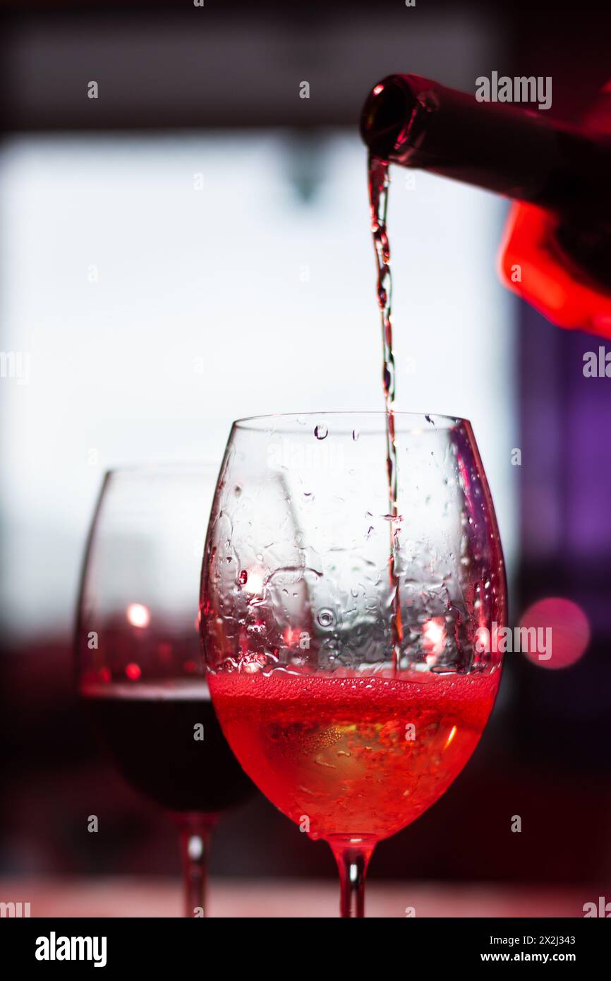 Silhouette de deux verres en verre avec du vin sur une table en bois. Bouteille servant un verre. Il est temps de se détendre. Banque D'Images