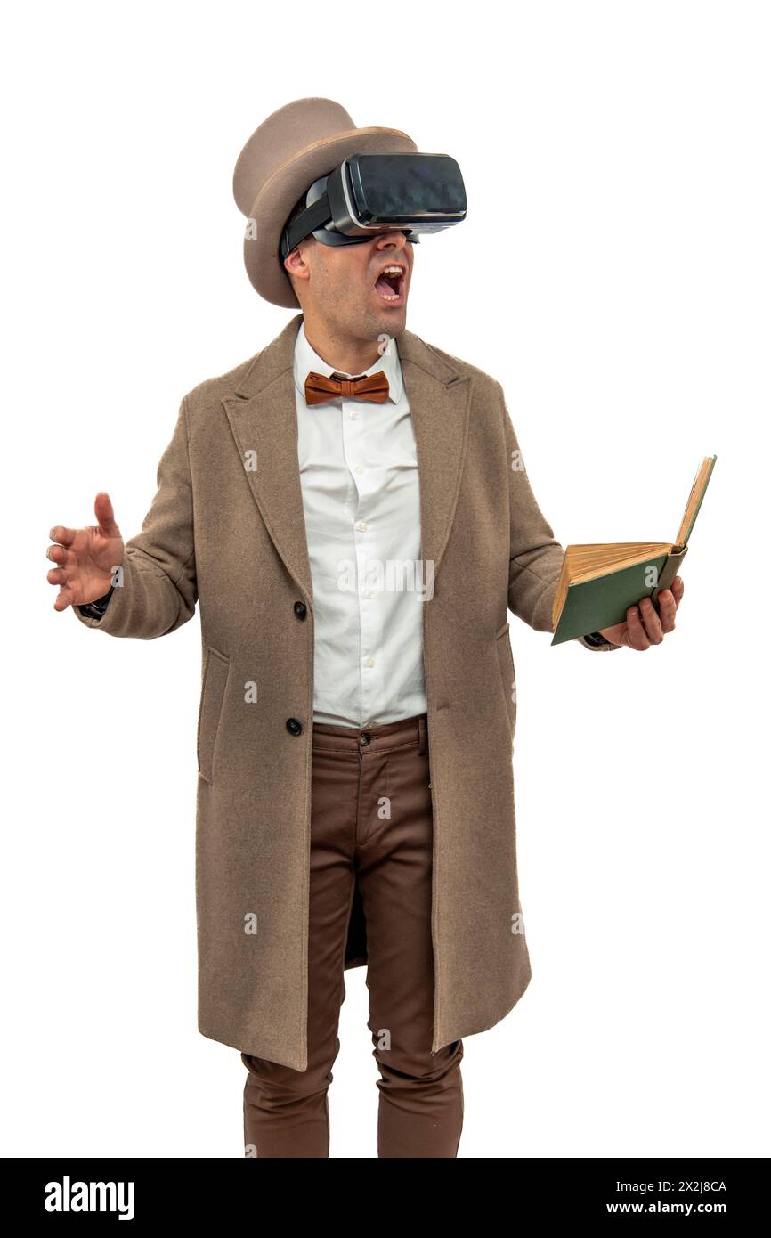 homme vêtu d'une tenue vintage du début du xxe siècle, y compris un chapeau melon et un trench-coat, portant des lunettes de réalité virtuelle tout en tenant un livre, regarde Banque D'Images