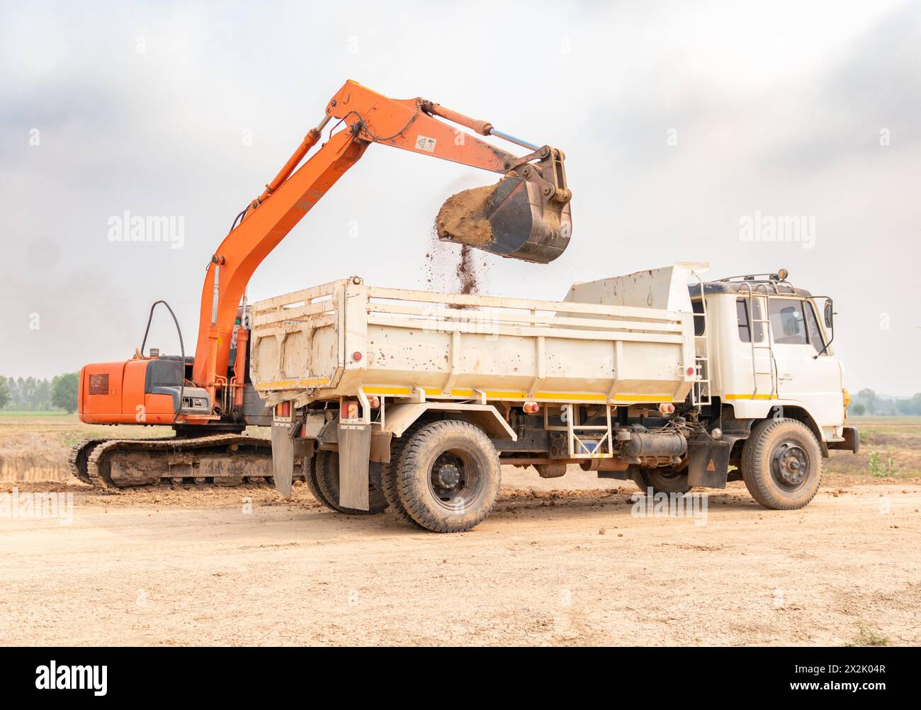 Chantier de construction avec backho. La pelle charge un camion de terre Banque D'Images