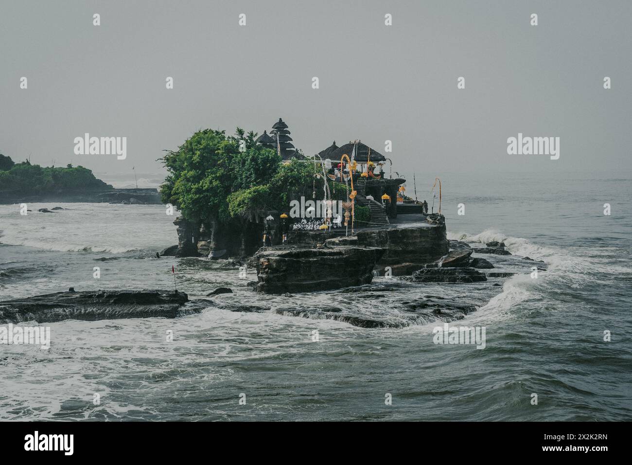 Un temple traditionnel perché sur une île rocheuse, entouré par les vagues brumeuses de l'océan, évoquant un sentiment de sérénité et de culture ancienne au milieu de la nature el Banque D'Images