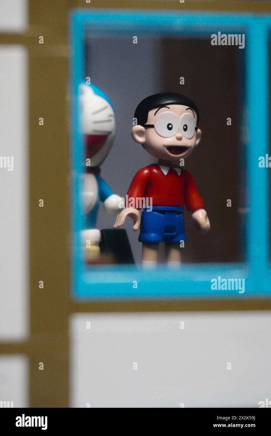 Figurines japonaises (Nobita et Doraemon) debout face à la fenêtre et visibles de la fenêtre Banque D'Images