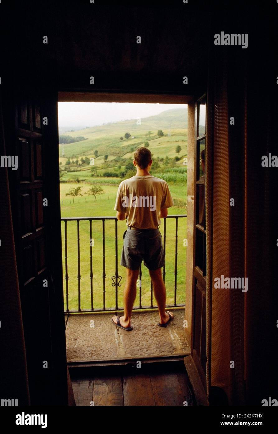 Homme à la fenêtre, regardant le paysage. Carmona, Cantabrie, Espagne. Banque D'Images