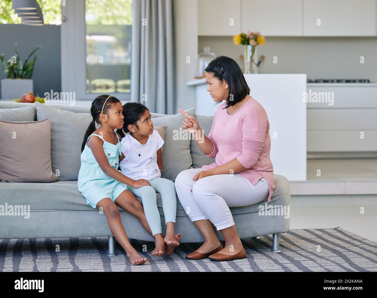 Mère, pointage et enfants en colère à la maison, discipline et communication ou parent strict dans la maison familiale. Salon, fille et canapé pour la punition Banque D'Images