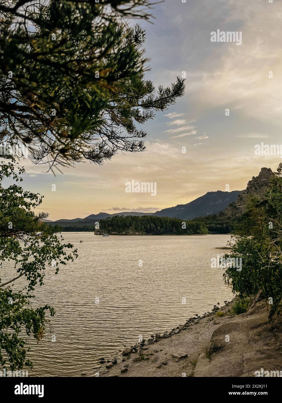 Calme lac Borovoe avec une rive rocheuse et des montagnes lointaines au coucher du soleil Banque D'Images
