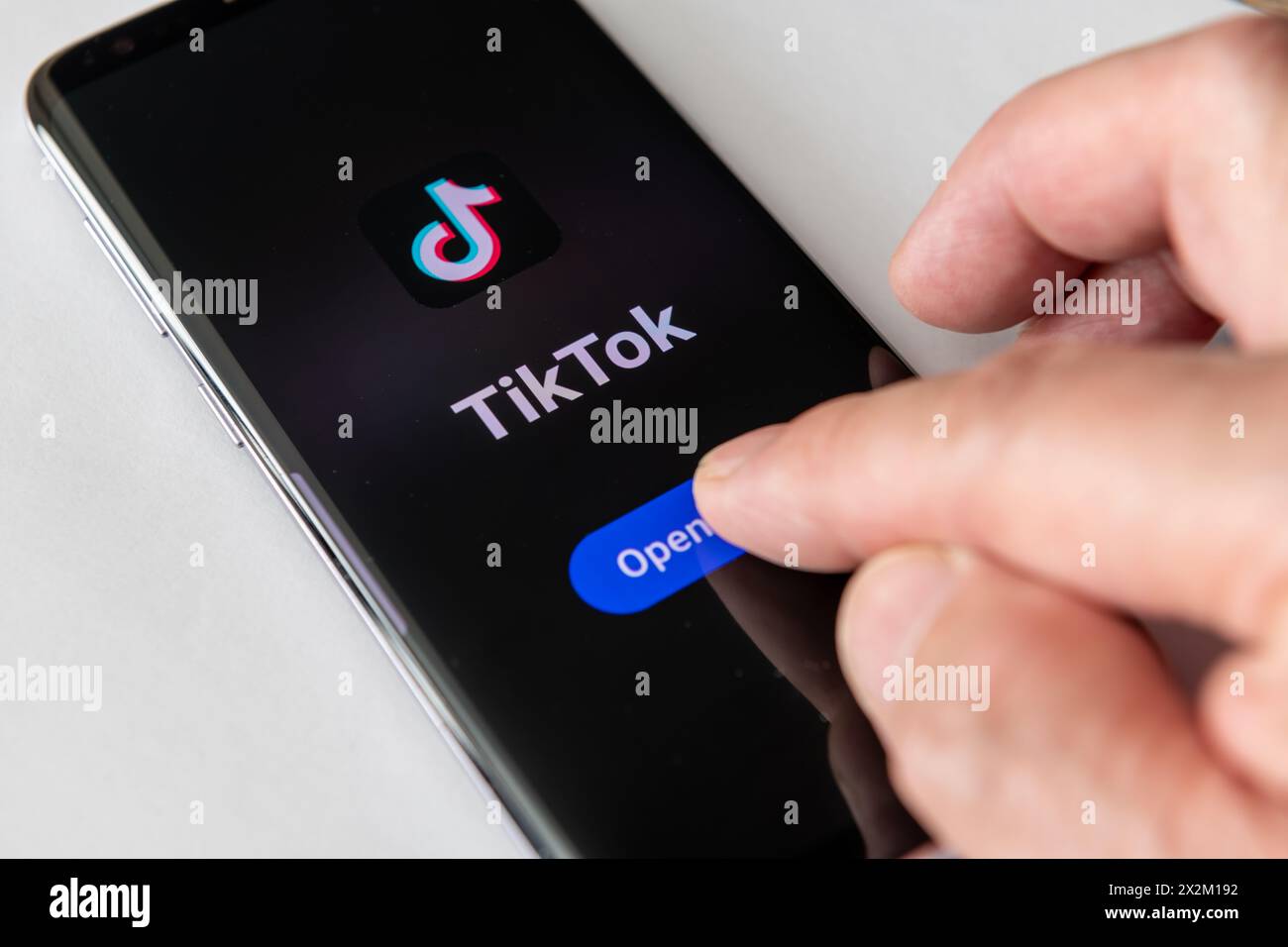 Londres. UK- 04.18.2024.L'application de partage de vidéo sur les médias sociaux TikTok et le logo de l'entreprise sur l'écran d'un téléphone intelligent avec un doigt appuyant sur OPE Banque D'Images