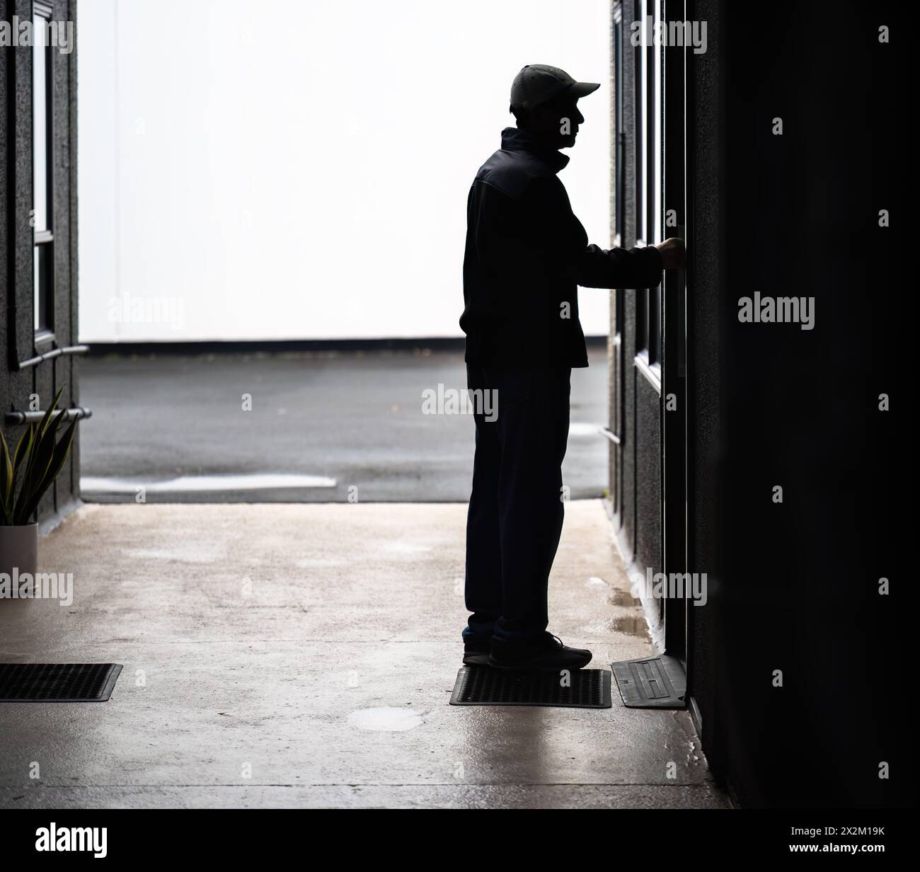 Silhouette d'un homme ouvrant une porte du bâtiment dans une ruelle sombre. Concept de film d'horreur. Banque D'Images