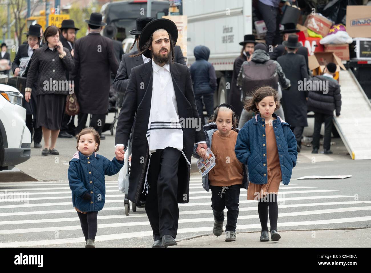 Un père juif hassidique et ses enfants dans une rue bondée de Brooklyn 2 jours avant la Pâque. À New York, 2024. Banque D'Images
