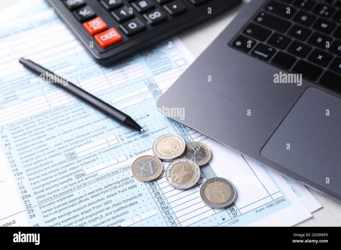 Formulaires fiscaux, pièces de monnaie, stylo, calculatrice et ordinateur portable sur la table, gros plan Banque D'Images
