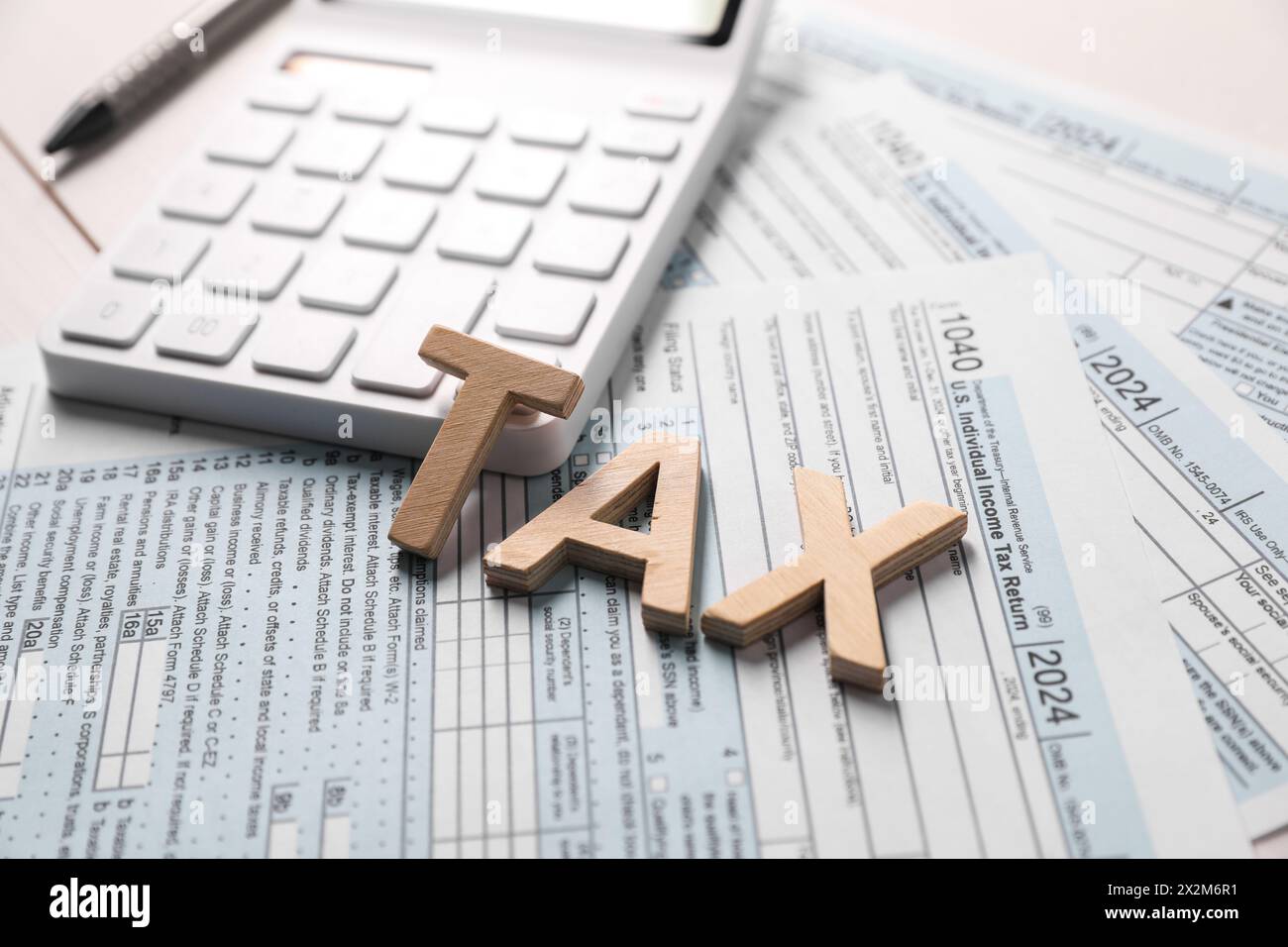 Word Tax fait avec des lettres en bois, calculatrice et documents sur la table, gros plan Banque D'Images