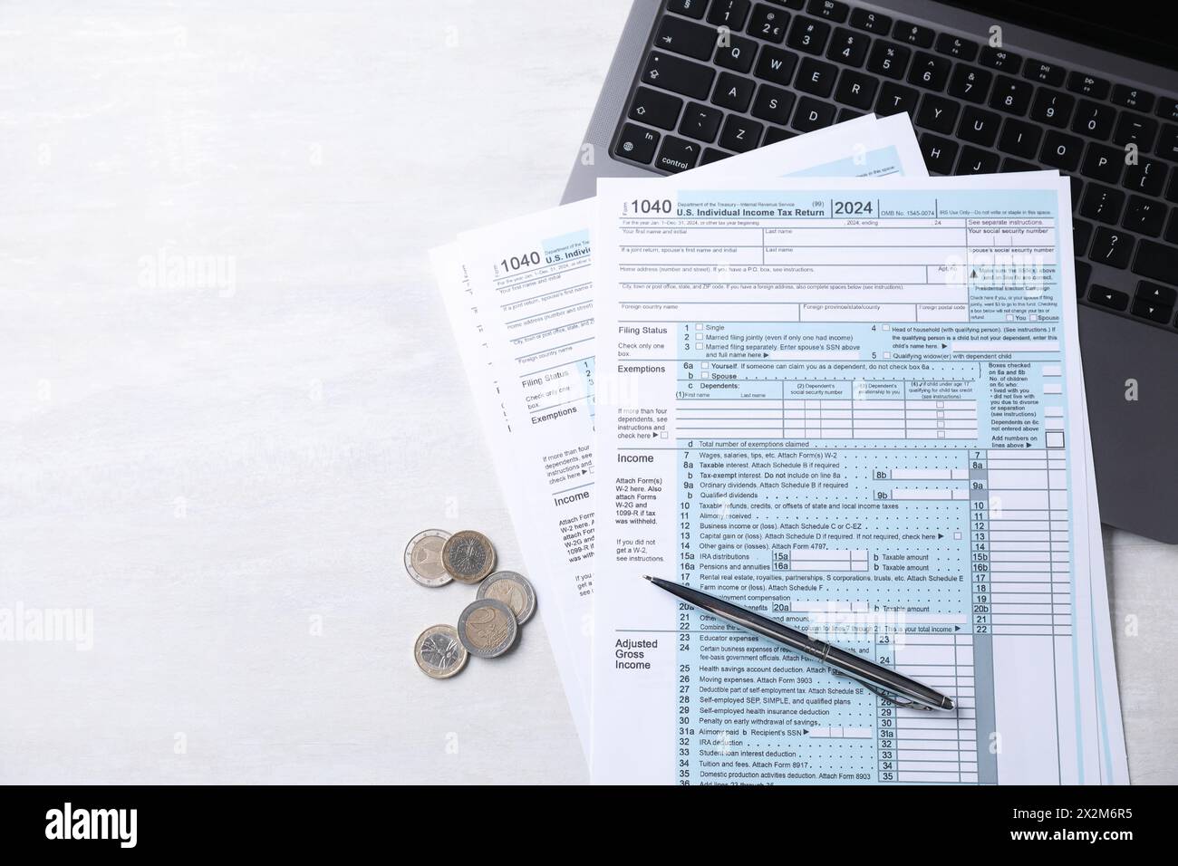 Formulaires fiscaux, pièces de monnaie, stylo et ordinateur portable sur la table gris clair, vue de dessus. Espace pour le texte Banque D'Images