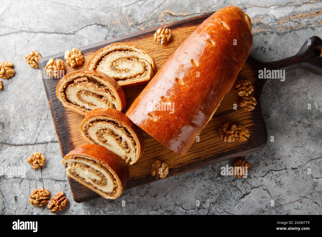 Rouleau de noix festif à base de pâte levée avec des noix et du miel gros plan sur une planche de bois sur la table. Vue horizontale de dessus Banque D'Images