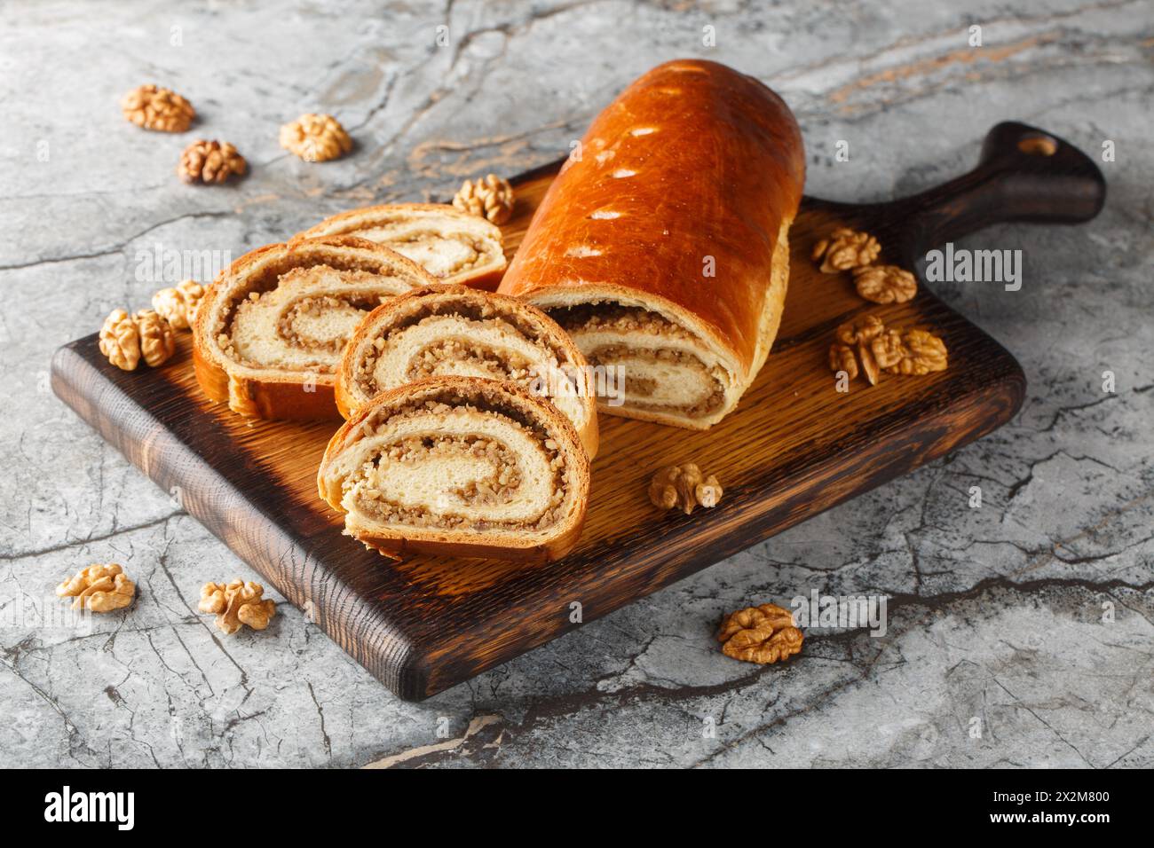 Rouleau de noix festif à base de pâte levée avec des noix et du miel gros plan sur une planche de bois sur la table. Horizontal Banque D'Images