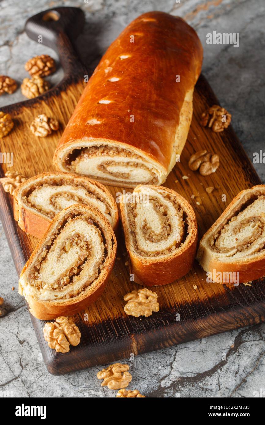 Rouleau de noix cuit à la maison, bejgli, pain sucré traditionnel farci de garniture de noix en gros plan sur la planche de bois sur la table. Vertical Banque D'Images