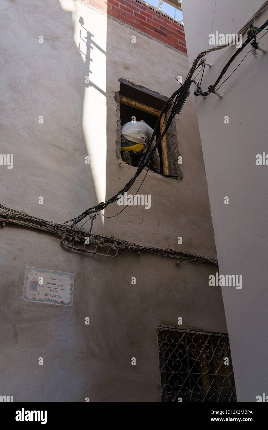 Tanger, Maroc. 6 février 2024 - homme travaillant sur une fenêtre ouverte du deuxième étage Banque D'Images