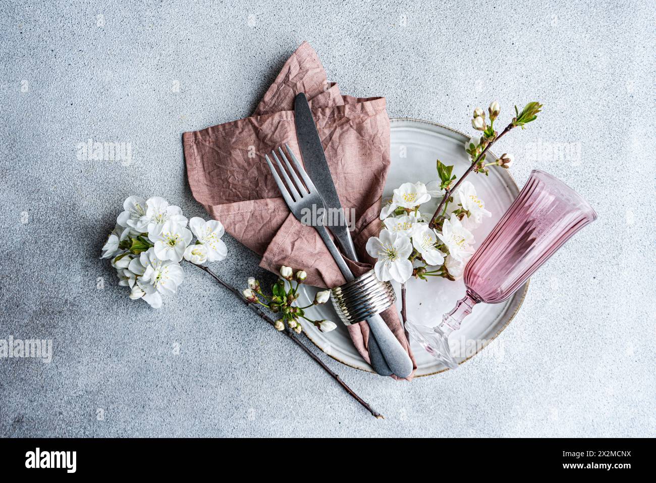 Décor de table élégant inspiré de la fleur de cerisier aux couleurs pastel, serviette texturée, argenterie et verre rose Banque D'Images