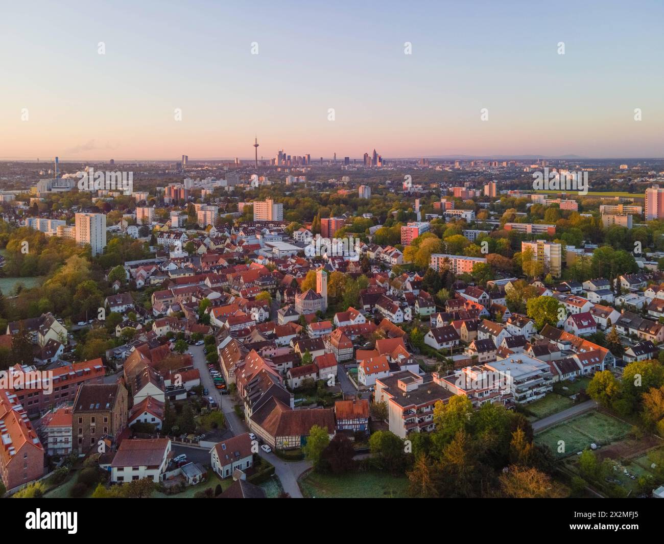 Der Frankfurter Stadtteil Niederursel am Morgen Das Morgenlicht der gerade aufgegangenen sonne fällt seitlich auf den alten Ortskern des Frankfurter Stadtteils Niederursel sowie auf die sich am Horizont erhebende Bankenskyline. Luftbild mit einer Drohne Frankfurt am main Niederursel Hessen Deutschland *** le quartier de Francfort de Niederursel le matin la lumière matinale du soleil nouvellement levé tombe latéralement sur le vieux centre-ville du quartier de Francfort de Niederursel et sur la ligne d'horizon de la banque s'élevant à l'horizon aérien vue avec un drone Frankfurt am main Niederursel Hesse Allemagne 2024- Banque D'Images