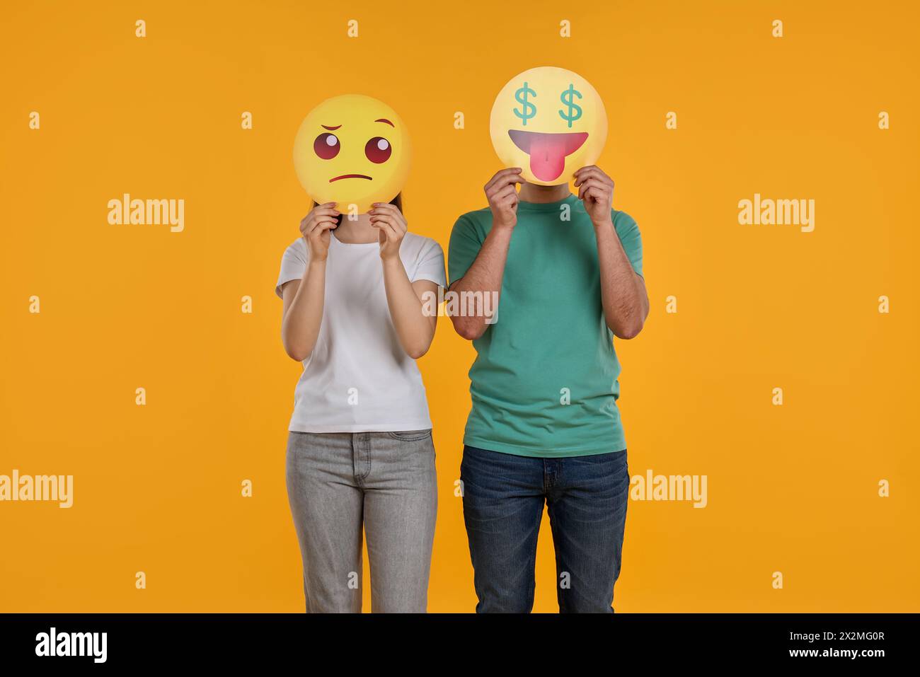 Personnes couvrant les visages avec des émoticônes sur fond jaune Banque D'Images