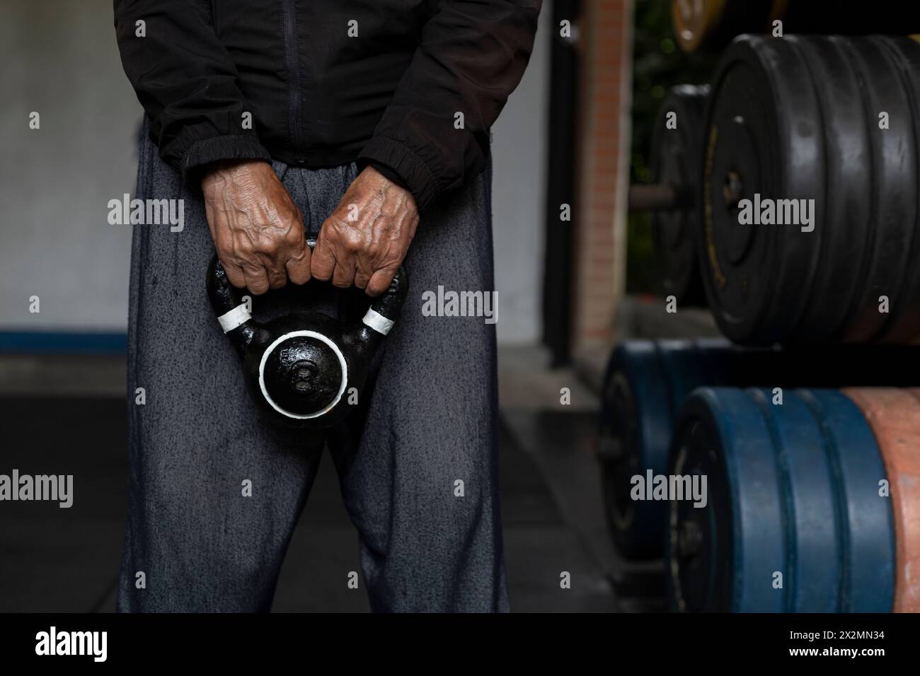 Homme senior latino-américain méconnaissable tenant une kettlebell avec les deux mains pendant ses séances de rééducation et de thérapie au gymnase. Vie saine Banque D'Images