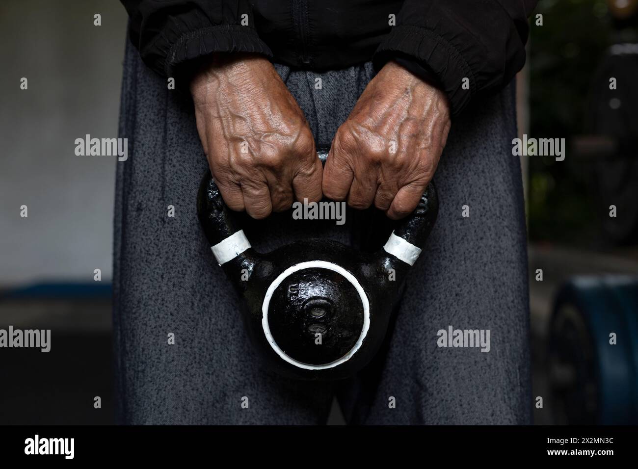 Homme senior latino-américain méconnaissable tenant une kettlebell avec les deux mains pendant ses séances de rééducation et de thérapie au gymnase. Vie saine Banque D'Images