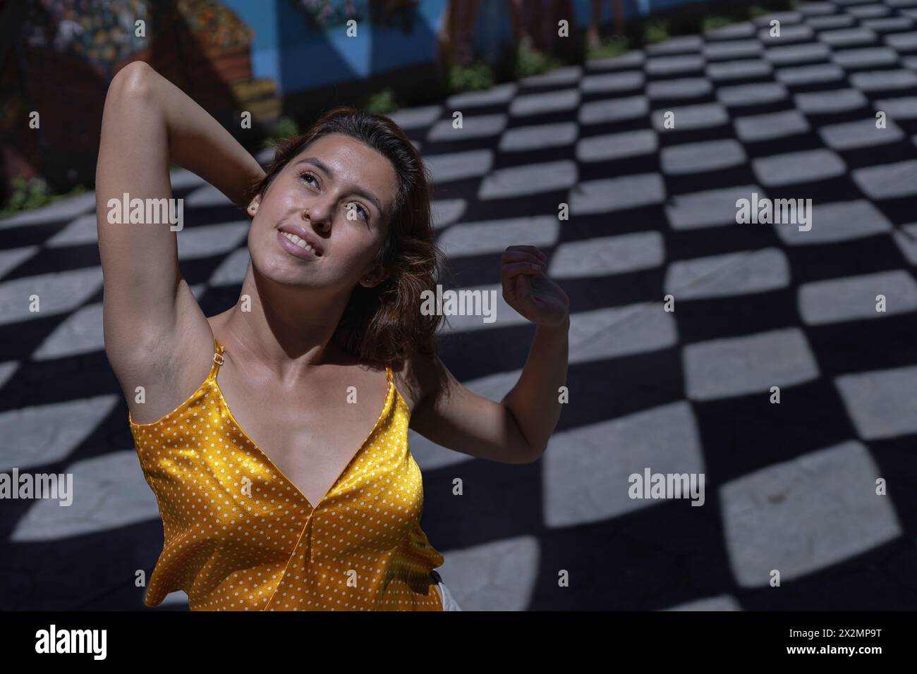 Portrait vu d'en haut d'une jeune femme latino-américaine avec une attitude détendue et positive. Fond sur le sol d'ombres avec des formes de losange. Concept Banque D'Images