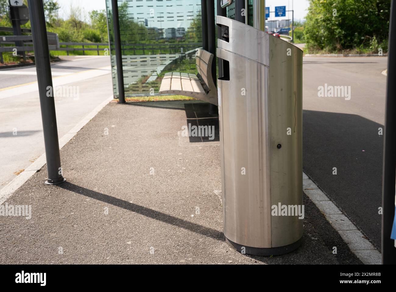 Poubelle moderne en acier inoxydable à un arrêt de bus avec banc. et toit comme protection contre les intempéries. Banque D'Images