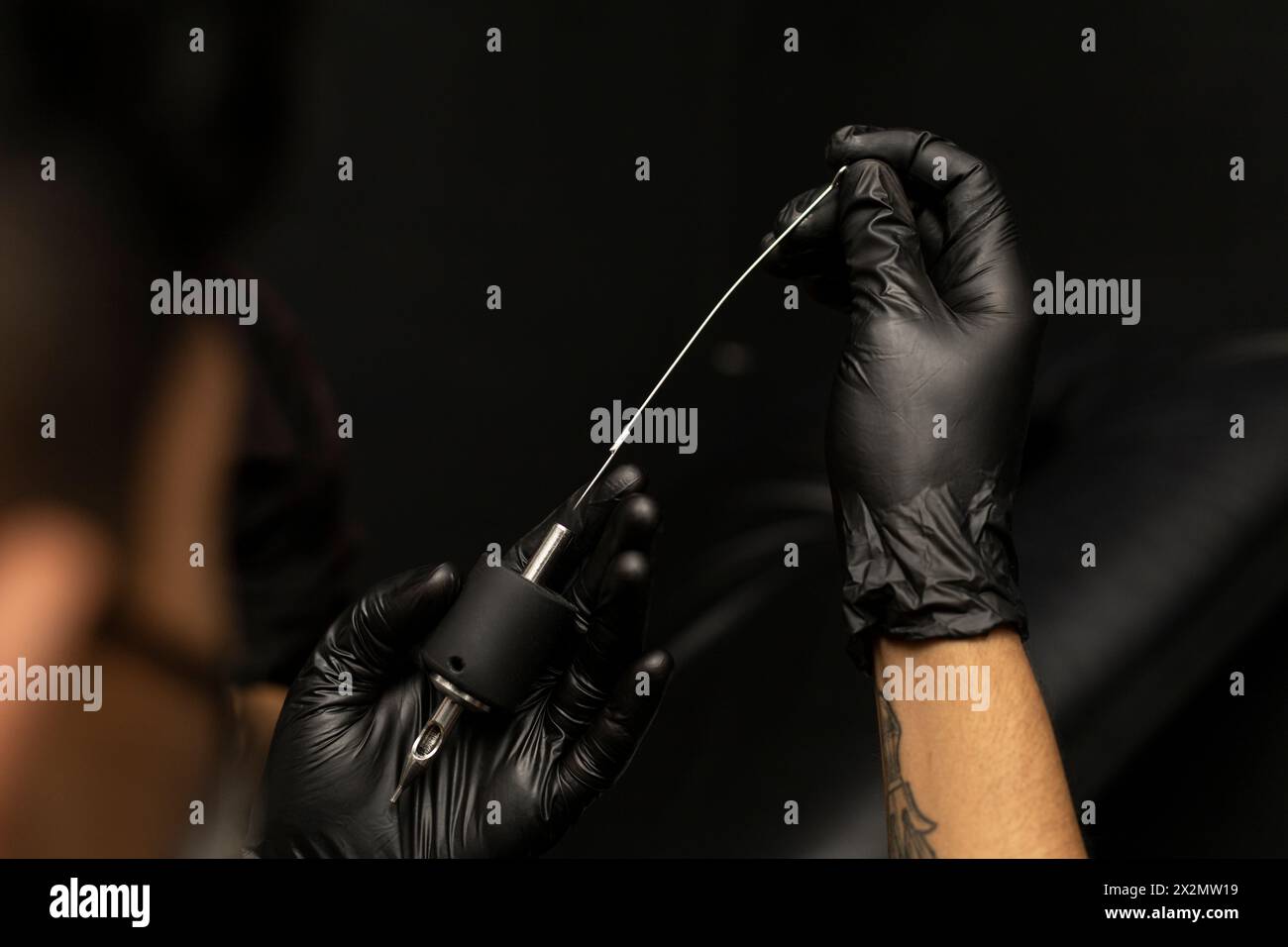 Tatoueur assemblant l'aiguille stérilisée dans la poignée. Porter des gants noirs. Concept d'art corporel Banque D'Images
