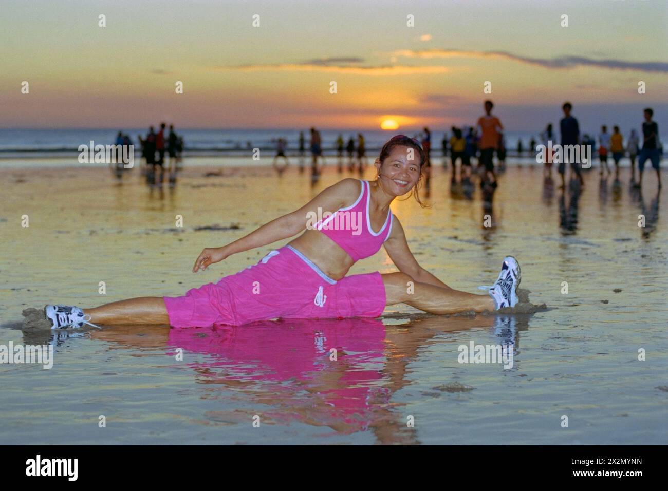 jeune femme indonésienne portant des vêtements de sport en passant par sa routine de maintien en forme sur une plage animée de kuta au coucher du soleil bali indonésie 2004 Banque D'Images