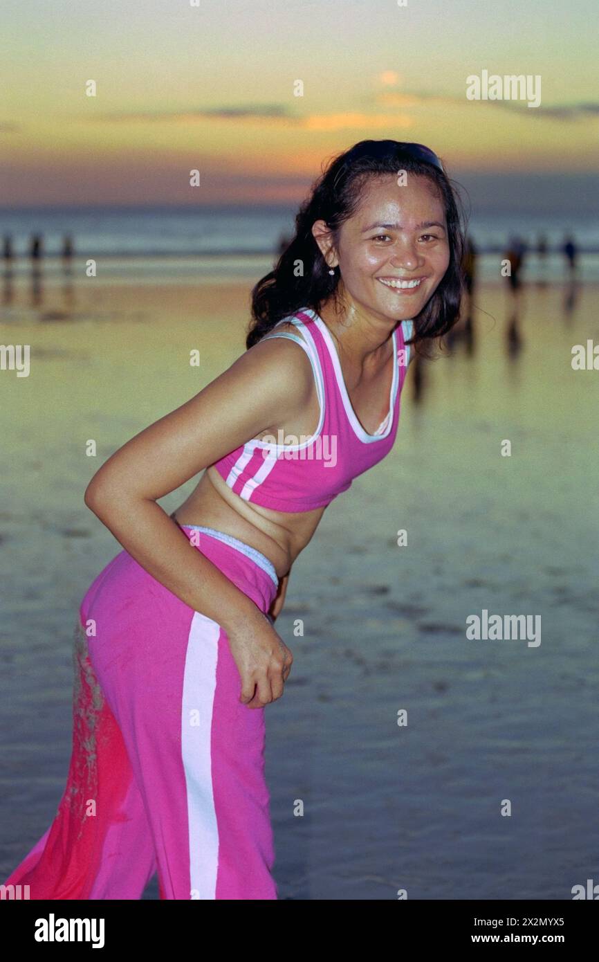 jeune femme indonésienne portant des vêtements de sport en passant par sa routine de maintien en forme sur une plage animée de kuta au coucher du soleil bali indonésie 2004 Banque D'Images