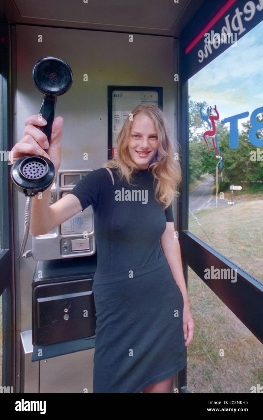 jeune souriant jolie blonde naturelle femelle tenant récepteur british telecom public phone payphone chalton hampshire angleterre des années 1990 Banque D'Images