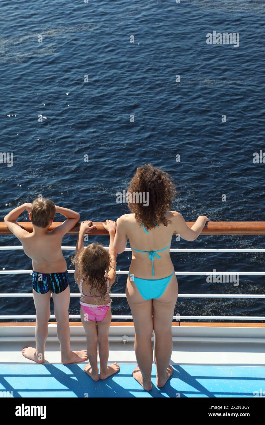 Dos de mère, fils et fille vêtus de maillots de bain debout sur le pont du navire et regardant l'eau Banque D'Images